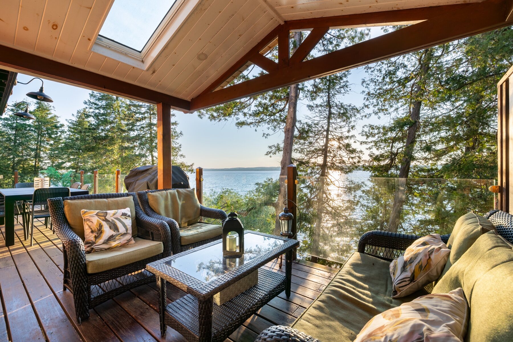 Covered deck with outdoor seating and a sunset view over Rice Lake