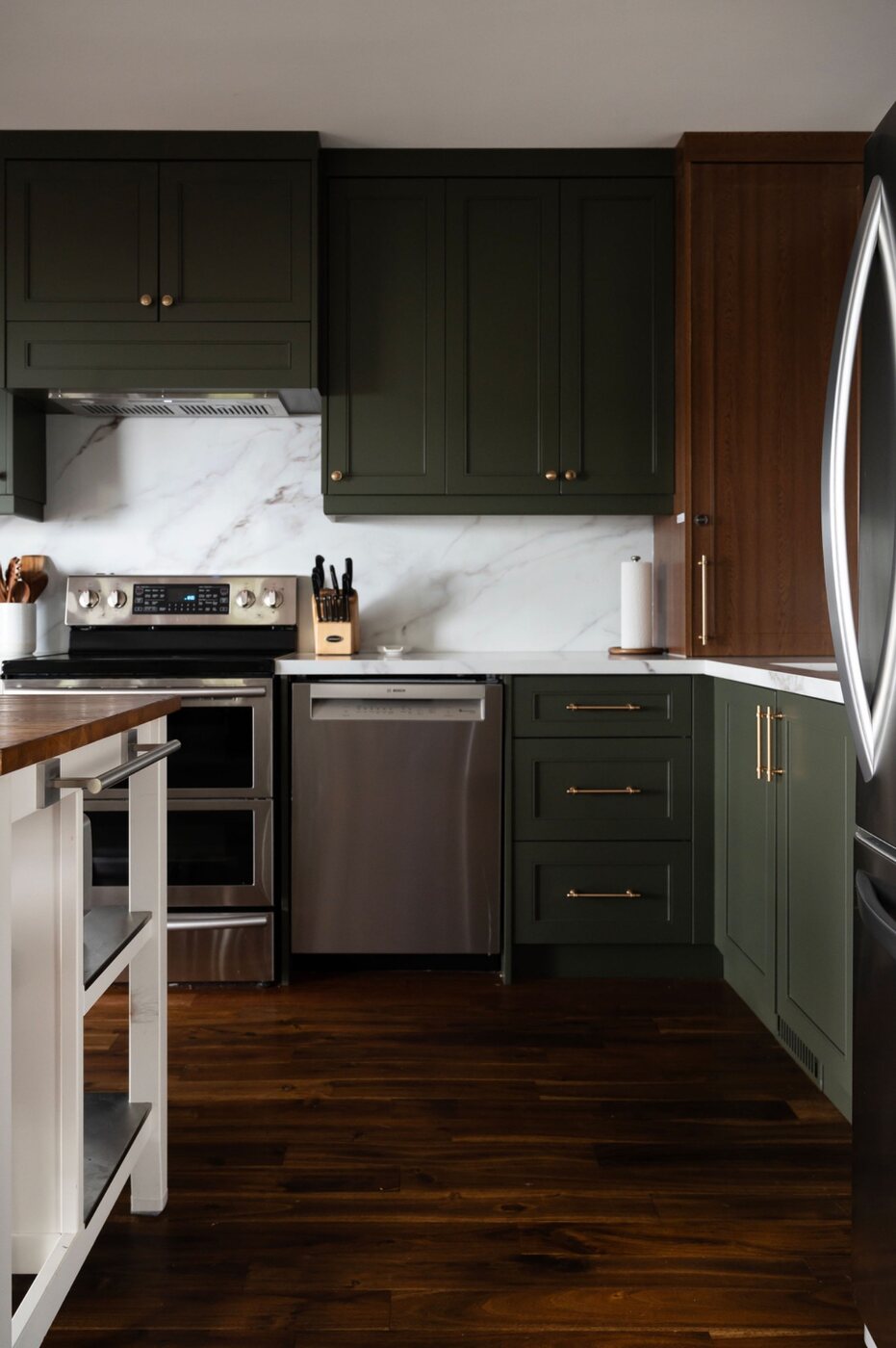 Renovated kitchen with stainless steel appliances and green cabinetry